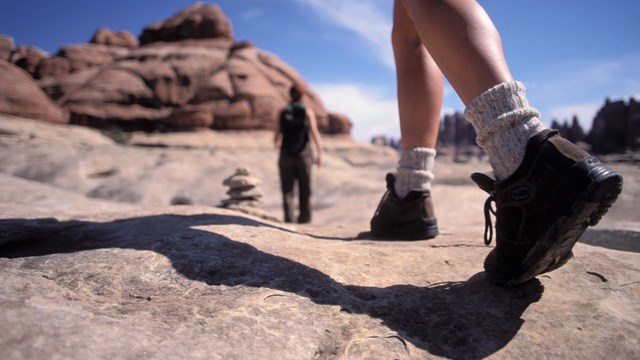 a close up a person's legs and hiking boots on a trail