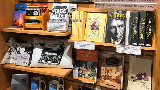 Bookshelf full of books, bookmarks, journals, pencils and other merchandise for sale at the store.