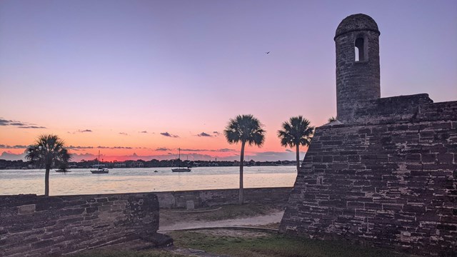 Sunrise with pink and purples hues with Castillo and Matanzas River in background.