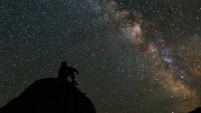 Silhouette of man looking at a dark starry sky. 