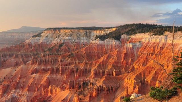 The red and white breaks formation glows at sunset with virga (rain) falling from clouds.