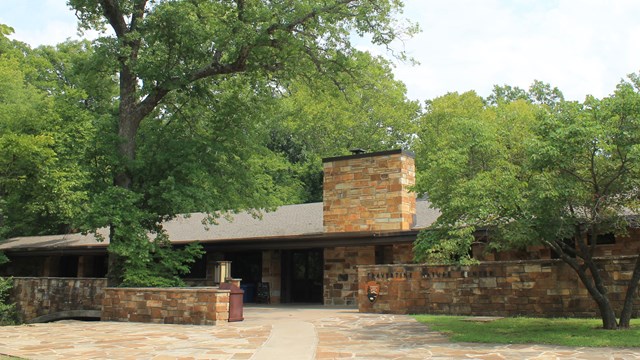 a stone building surrounded by green trees