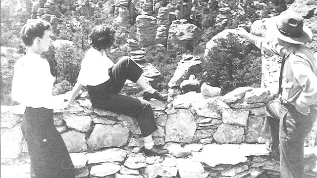 Photo of two women and a ranger pointing at rock formations.