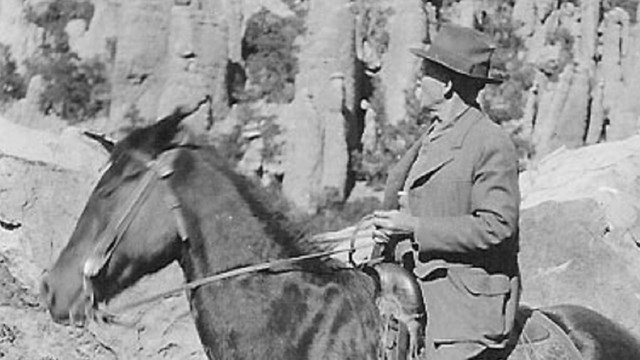 Man on horseback in front of rock formations