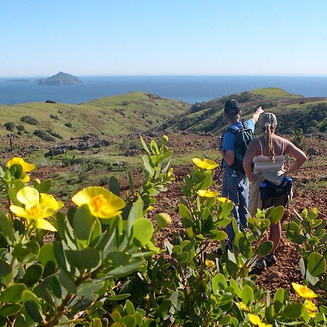 Hikers on mountain overlooking ocean and islands. ©Kathy de-Wet Oleson