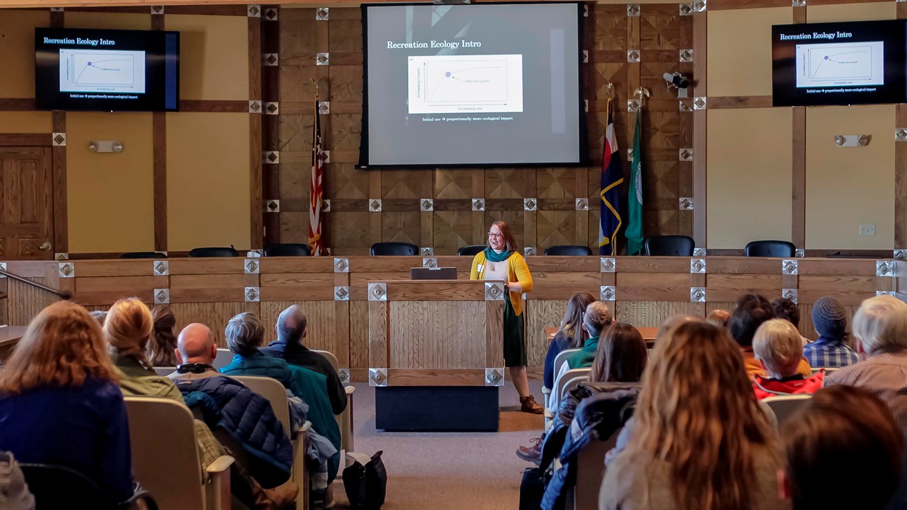 Researcher presents at a podium to an auditorium of people.