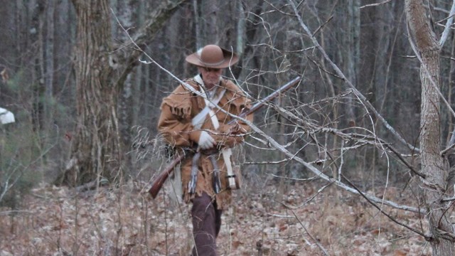 Reenactors in hunting frock walks through woods