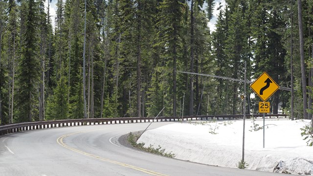  a guard rail on the left curves with OR Hwy 62, on the right is a slow 25 mph sign 