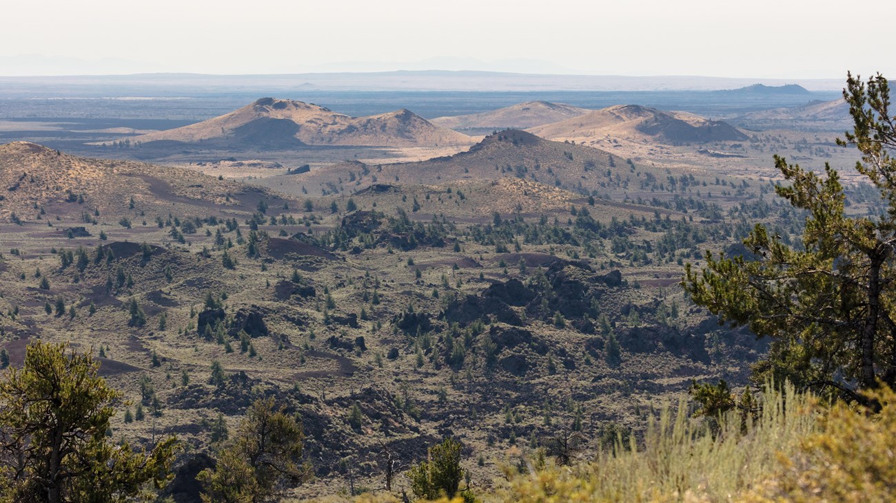 Lava landscape featuring cinder cones, craters, and sagebrush steppe. 