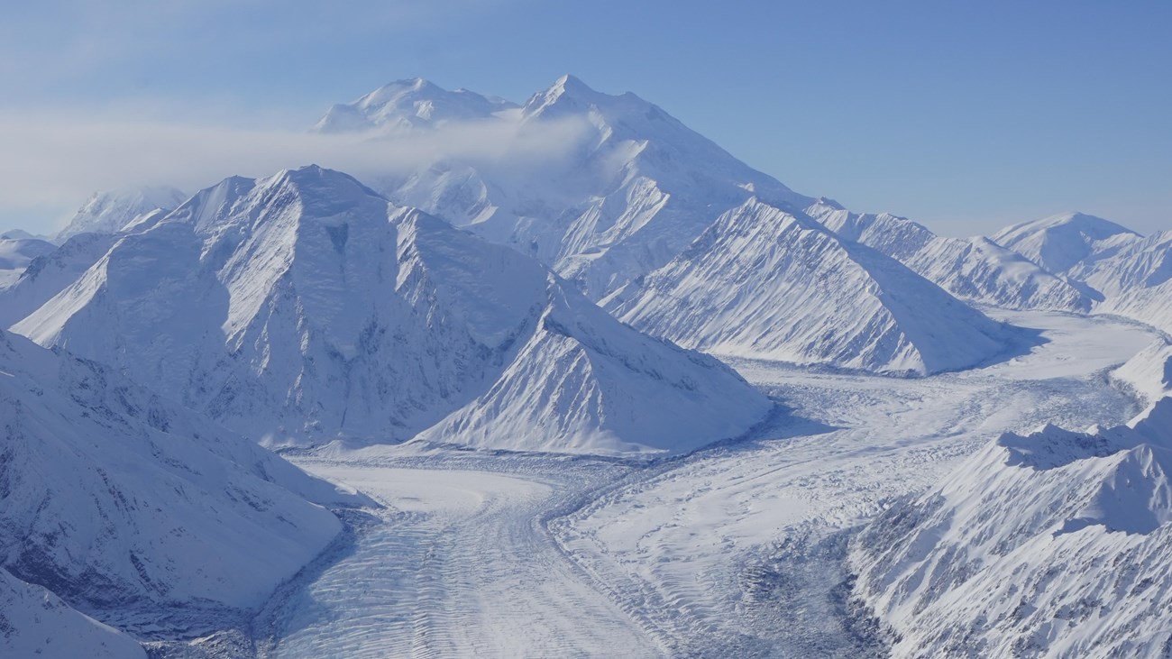 a huge snowy mountain with vast glacier flowing off it