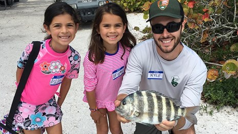 Two children and Park Ranger hold up stripped Sheepshead Fish
