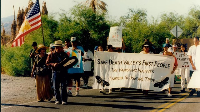 Group marching in street with sign stating: Save Death Valley's First People.