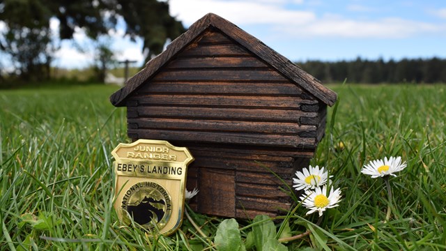 Jr Ranger badge in front of replica block house.