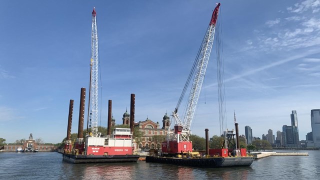 Tall cranes work on barges just off Ellis Island