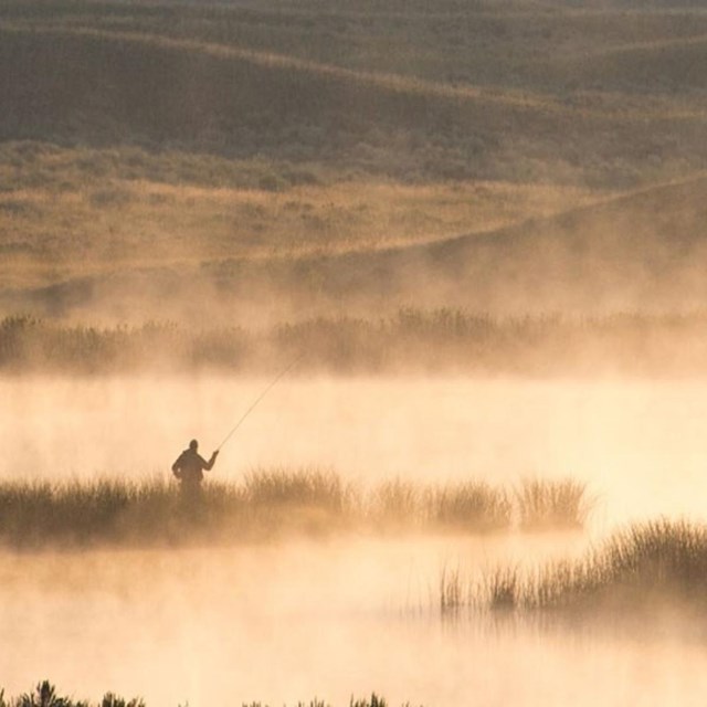 Angler fishing in lakes with steam rising. 