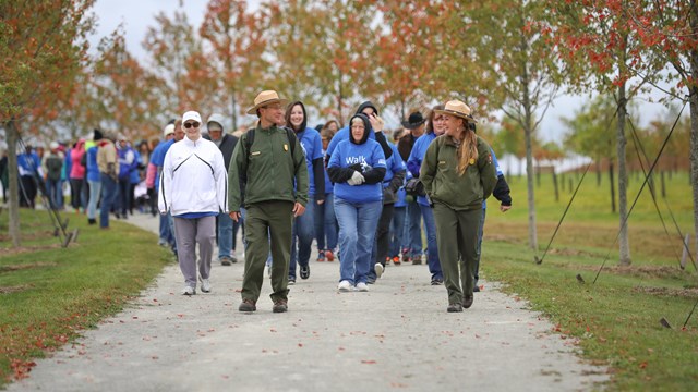 Two rangers leading a group down a trail.