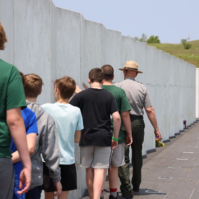 A ranger walking along the Wall of Names with a group of students.