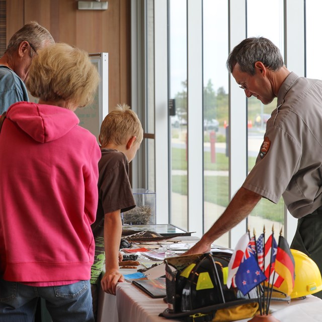 Ranger speaks with young child over items on a table