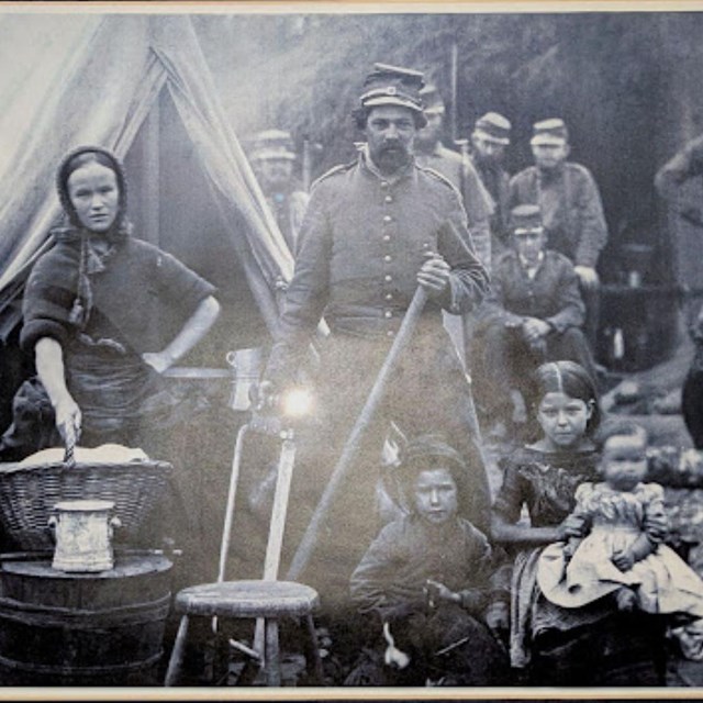 An old family photograph showing parents and children standing together in front of a tent.