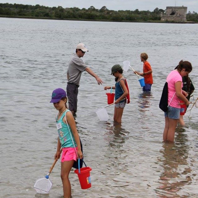 Teacher in river with kids at the fort. 