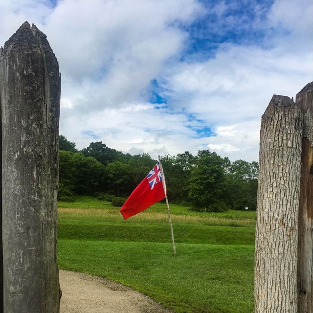 A red British flag flies outside the stockade door