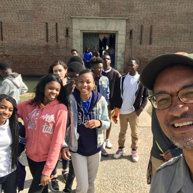 Ranger with students standing outside fort entry, fort in background