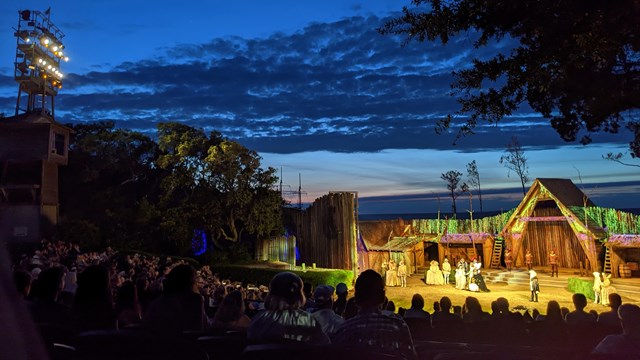 Outdoor amphitheater with rows of seats leading to a stage set.