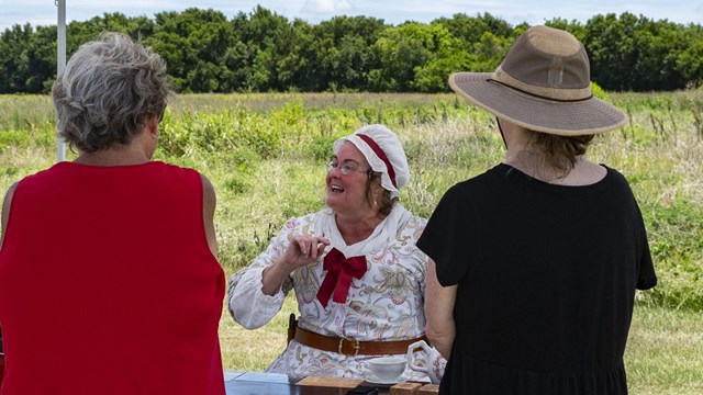 A living history volunteer talks with visitors