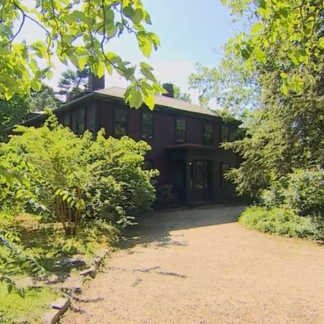 Dirt path leading to large building with trees around it