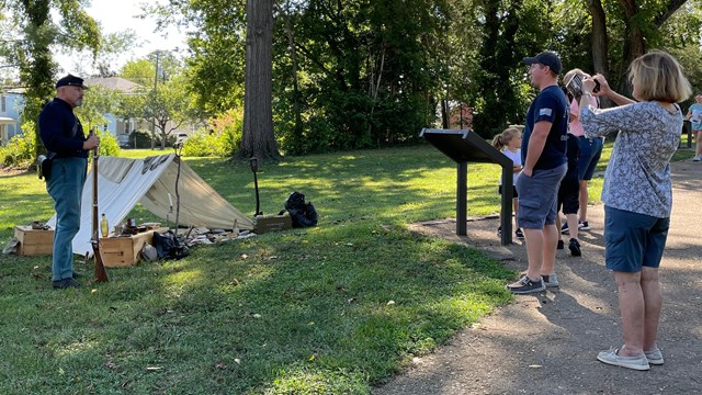 Living historian dressed as US civil war soldier with tent speaks to visitors