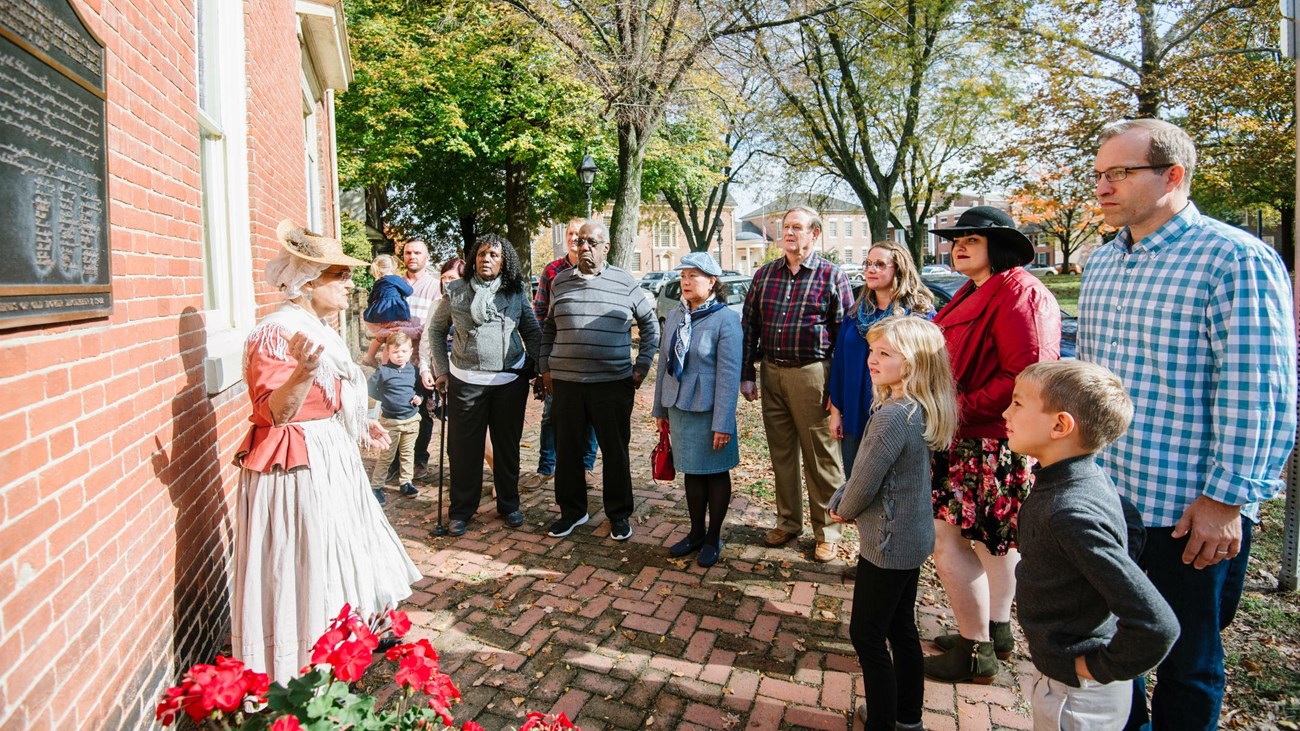 A woman in historical clothing leads a tour. 