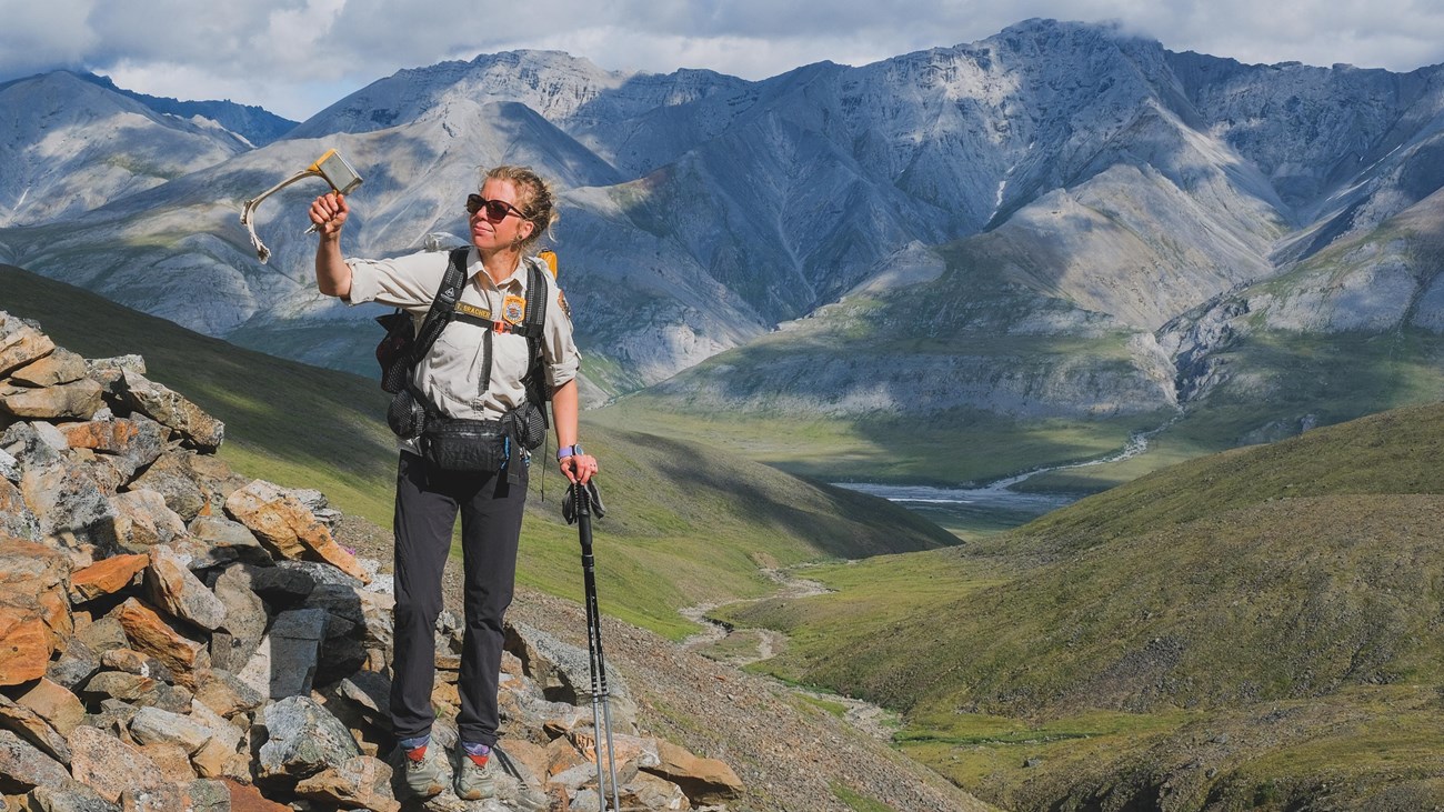 A backcountry ranger stands high in the mountains of Gates of the Arctic, holding a caribou collar