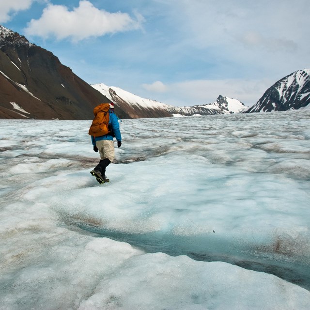 hiker in winter gear hiking on glacial ice