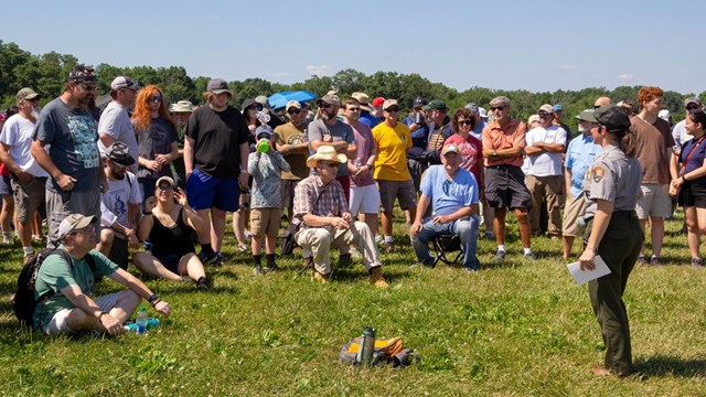 A Park Ranger stands and speaks to a group of people
