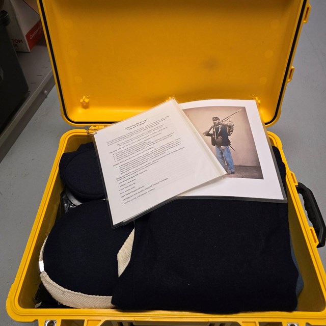 An open yellow trunk containing a Civil War solder's uniform.