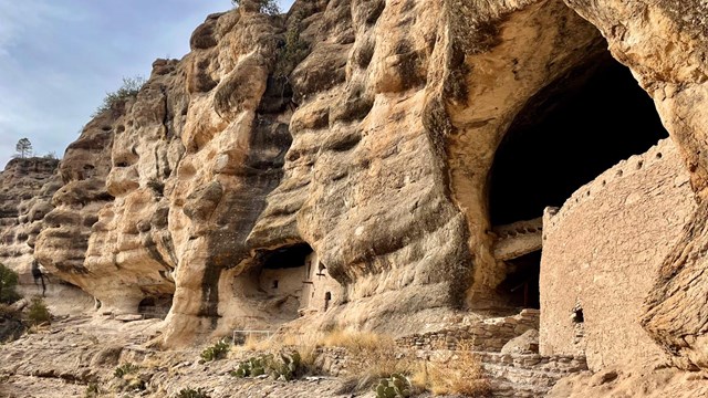 The sun lights up the entrances to the alcoves that contain the Gila Cliff Dwellings