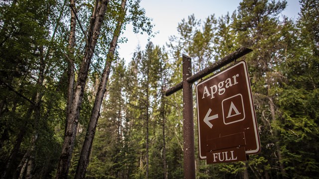 A hanging brown sign with white letters reads "Apgar Campground Full."