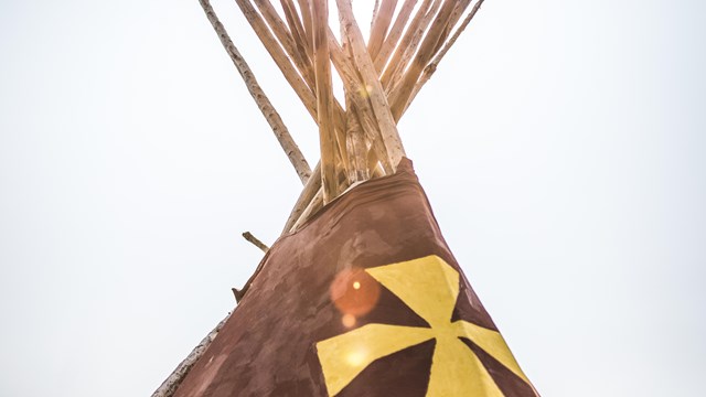 The top of a Blackfeet lodge is highlighted by the sun.