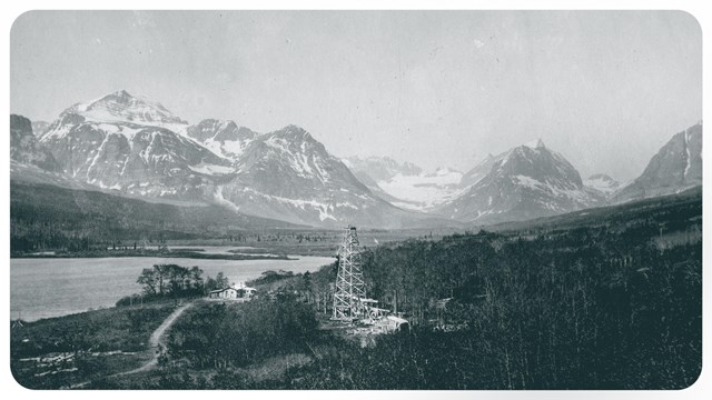 black and white of an oil well in the foreground and Grinnell Glacier behind it