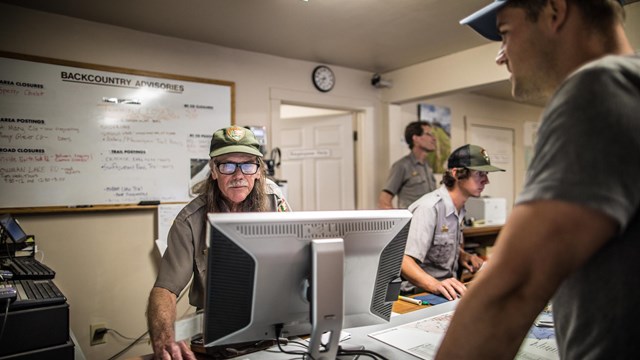 Park Rangers assists a visitor with their wilderness itinerary.