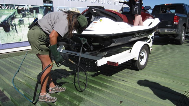 Ranger sprays personal watercraft at decontamination station