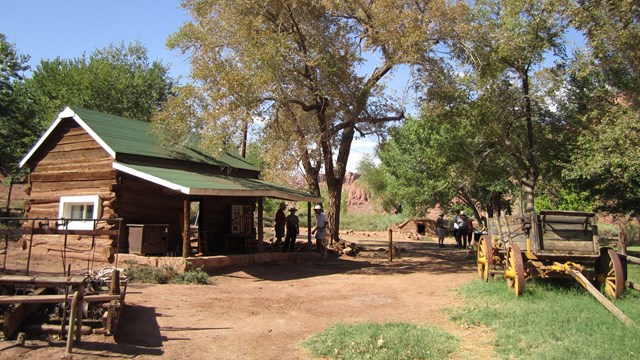 A wagon sits next to a historic log ranch house.