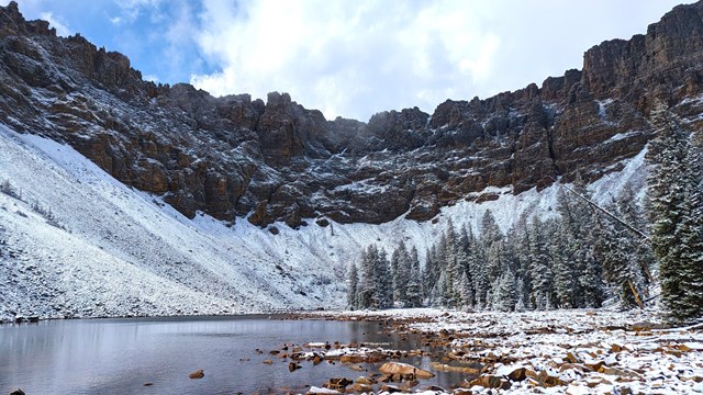 A shimmering lake is surrounded by mountains and a fresh layer of perfect white snow