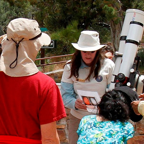 volunteers help visitors view the sun through a solar telescope.