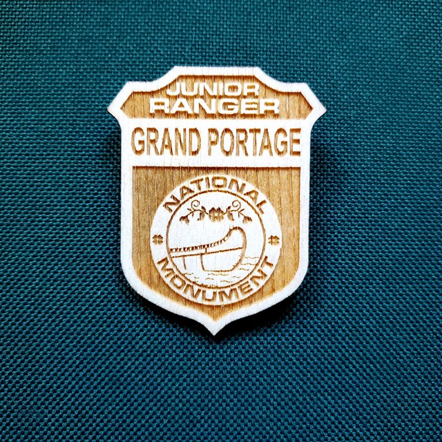 A wooden Junior Ranger badge showing a canoe.