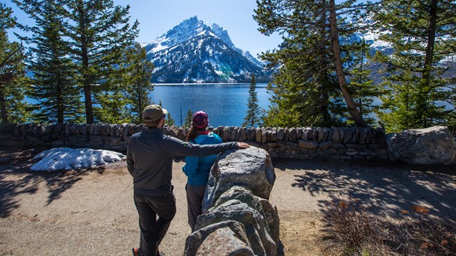 Two visitors enjoy the view of a lake from at an overlook