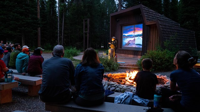 A ranger talks to kids outside.