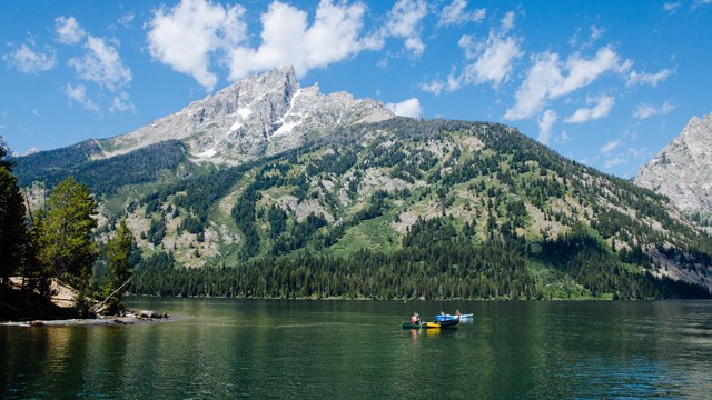 Boats on a lake at the base of a mountain.