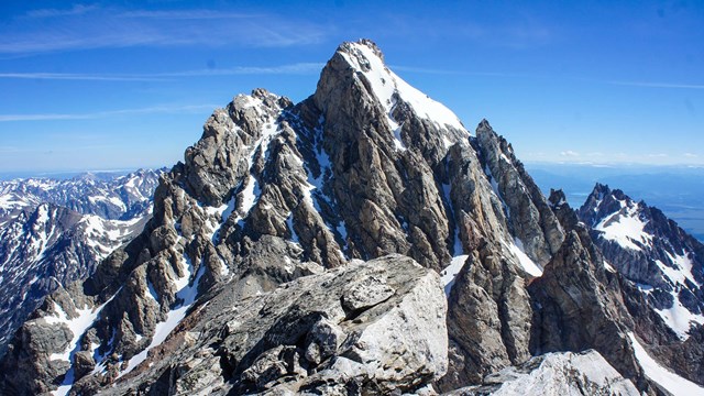 A sharp rocky mountain with patches of snow