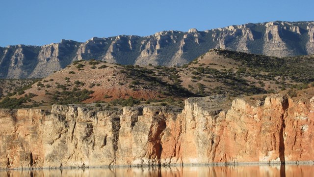 Two layers of vertical cliffs rise above a large lake.